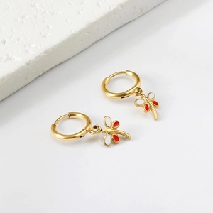 Detailed macro of gold dragonfly hoop earrings with red and white enamel finish