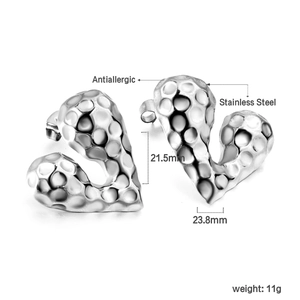 Macro view of heart-shaped stainless steel earrings with textured hammered finish