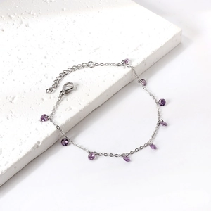 Elegant silver stainless steel bracelet with purple zircon pendants on marble surface