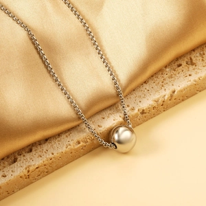 Collier minimaliste en acier argenté avec pendentif boule poli sur fond de soie douce