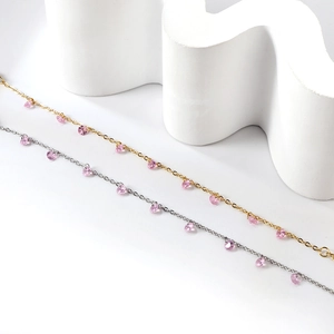 Détail de bracelets fins or et argent avec pendentifs en cristal de cœur rose