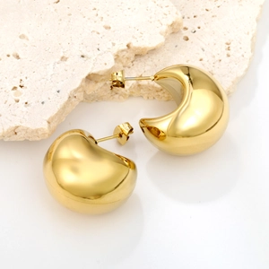 Polished chunky gold geometric hollow ball earrings displayed on minimalist stone surface