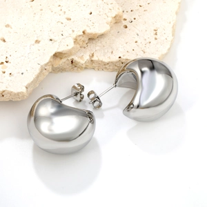 Polished silver teardrop stud earrings with a 18K plated mirror finish on stone background