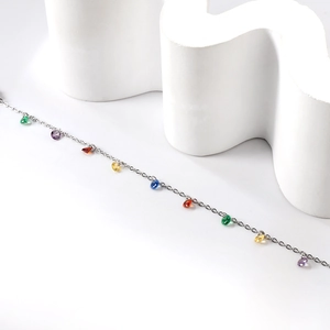 Détail d'un bracelet en argent fin avec des breloques en pierres colorées sur support blanc