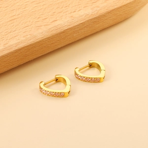 Elegant gold heart earrings with pink zircon stones on a minimalist beige background