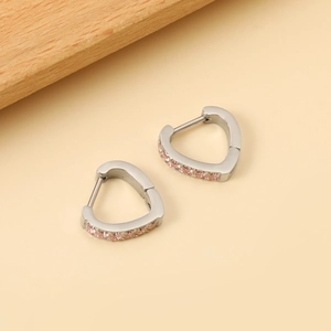 Elegant heart-shaped silver earrings with pink zircon stones on a warm beige backdrop
