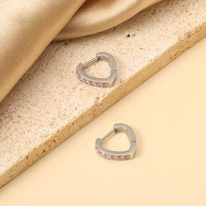 Close-up of heart-shaped stainless steel earrings with pink crystals on stone