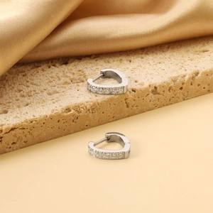 Detailed close-up of heart-shaped silver hoop earrings with shimmering pavé set crystals