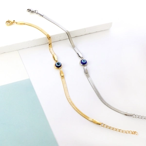 Detail of gold and silver snake chain bracelets with blue evil eye charms and lobster clasps