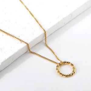 Détail du pendentif anneau doré torsadé avec chaîne fine sur un présentoir blanc