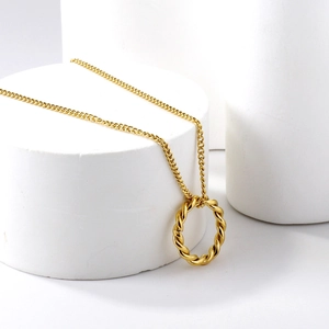 Pendentif anneau torsadé doré sur une fine chaîne maille forçat avec fond blanc minimaliste