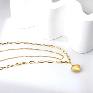 Gros plan détaillé d'un collier doré multicouche avec pendentif cœur sur présentoir