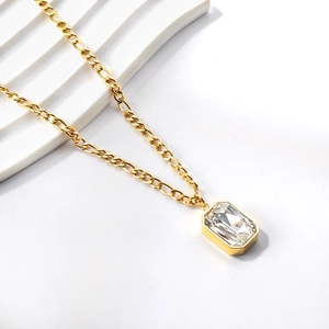 Close-up of gold Figaro chain featuring a large rectangular emerald-cut clear crystal pendant