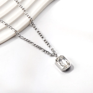 Close-up of a rectangular crystal pendant on a silver Figaro chain necklace