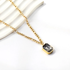 Detail of a vintage gold-plated Figaro chain necklace featuring a dark gray rectangular stone