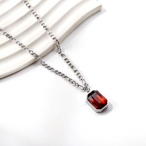 Detailed macro view of rectangle red gemstone pendant on silver Figaro chain necklace