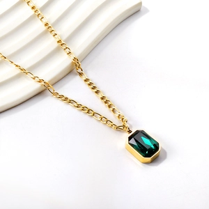 Detailed close-up of emerald-cut green crystal pendant on a gold stainless steel chain