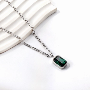 Detail of silver Figaro chain necklace with a rectangular emerald green gemstone pendant