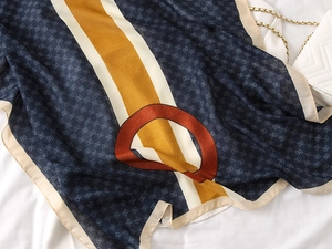 Detailed view of luxury silk scarf texture with classic geometric pattern and handbag