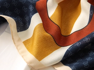 Macro detail of silk-texture scarf with geometric patterns and monogram print