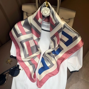 Detail of silk-like scarf with geometric patterns styled on a white knitted top