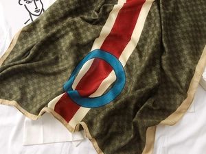 Detailed view of olive green cotton-linen scarf with retro red stripes and blue ring pattern