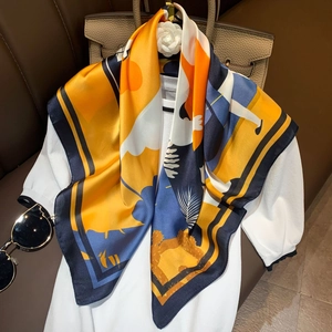 Elegant display of an abstract print silk scarf draped over a white top with a handbag