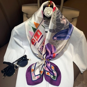 Close-up of elegant floral silk scarf styled with a gold ring and camel leather bag