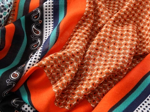 Detailed close-up of paisley and polka dot patterns on soft orange and turquoise scarf