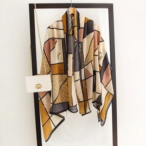 Detail of a geometric color-block silk scarf draped over a display rack with a handbag