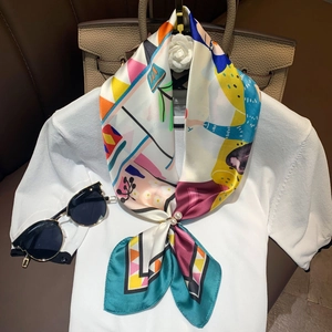 Detail of silk-like printed scarf featuring vibrant geometric patterns and pearl buckle