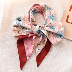 Pink narrow silk twilly scarf with blue orchid patterns and wine red ends displayed in a bow