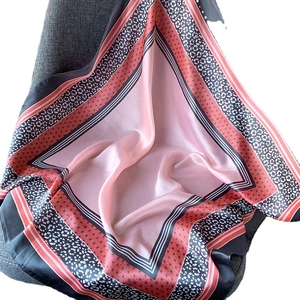 Écharpe rose en soie synthétique à pois et motifs floraux sur une chaise grise