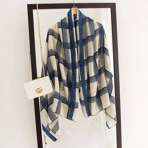 Detail of blue and white plaid scarf with fine stitching and hanging tag on wooden hanger