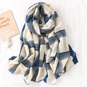 Detail of a beige linen cotton shawl with dark blue striped pattern and tassels