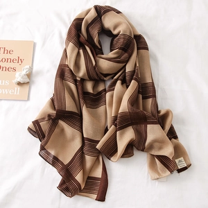 Detailed view of brown and beige checkered cotton scarf draped over white bed sheets