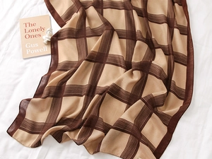 Detailed close-up of brown and beige grid pattern scarf with fine edge stitching