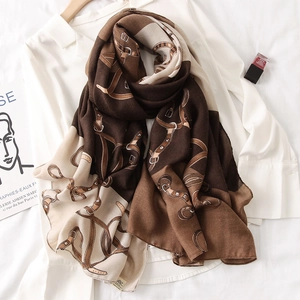 Detail of soft vintage scarf with horse harness print and belt buckle motifs on white shirt