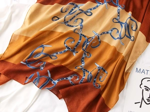 Detail of vintage belt buckle print on soft orange and brown square silk scarf shawl