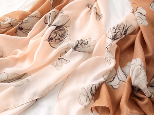 Detail of elegant orange-pink and brown scarf with hand-painted black and white floral prints