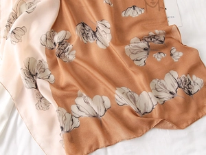 Close-up of caramel and beige floral print scarf with soft silk-like texture and sheen