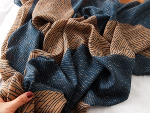 Detail showing the soft texture and geometric knit pattern of the navy and orange scarf