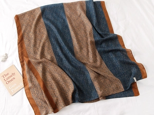 Detail of elegant striped scarf with geometric prints and smooth silk-like texture