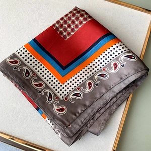 Dettaglio di un foulard in seta con blocchi di colore rosso e motivi paisley in un vassoio