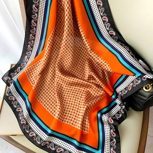 Dettaglio di sciarpa in seta paisley in arancione vivace e blu navy con motivi geometrici