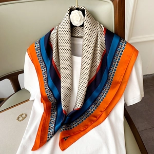 Dettaglio di un foulard in seta a pois geometrici drappeggiato su una maglietta bianca
