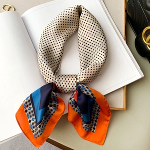 Dettaglio di foulard setoso a pois con motivi paisley su una rivista bianca