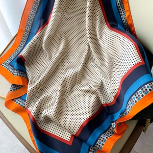 Dettaglio foulard in seta con motivi paisley, pois neri e bordi geometrici colorati