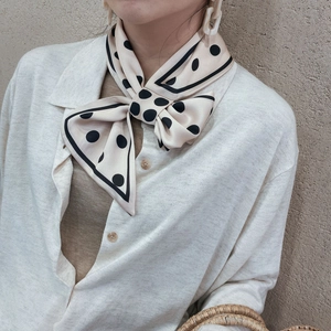 Gros plan d'un foulard en soie à pois noué en nœud avec des bords contrastés noir et beige