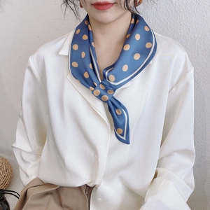 Gros plan d'un foulard en soie à pois bleus et marrons noué avec un fini satiné